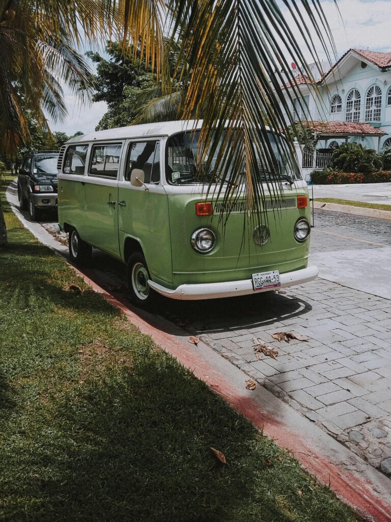 A classic green van parked on a sunny street under palm trees, evoking a retro travel vibe. Inno'van